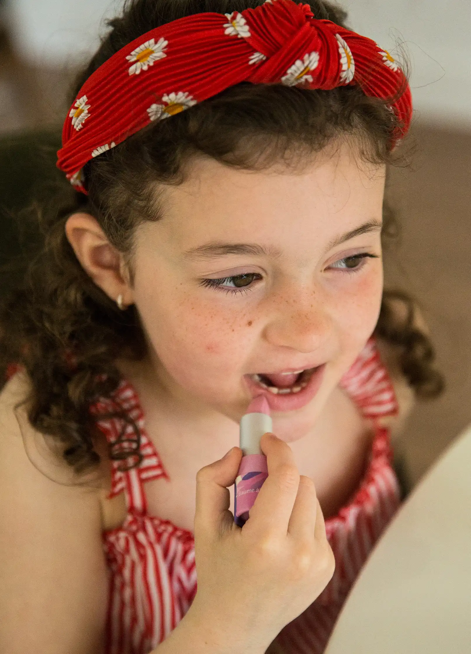 Petite fille avec du baume à lèvre BIO à la framboise