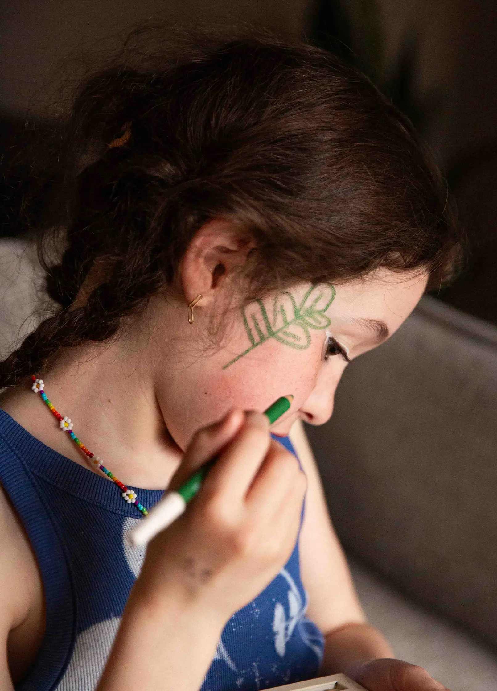 petite fille qui se maquille la joue avec un crayon fin