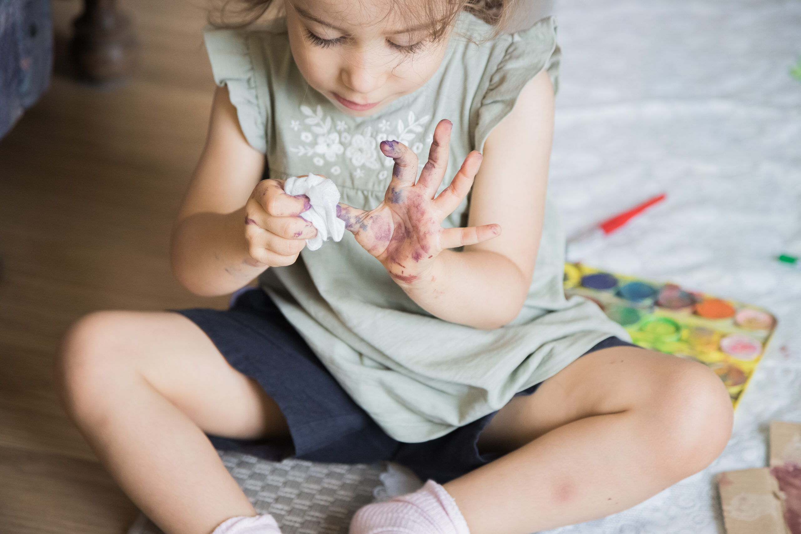 Kind, das sich die Finger mit einem Papiertuch abwischt